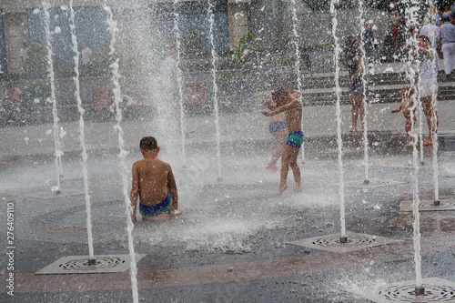 Children bathe in the fountain in hot summer day