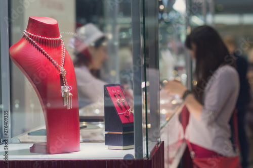 Various jewelry in a show-window and buyers in jewelry store