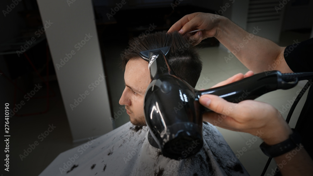 Barber shop. Man in barber's chair, hairdresser styling his hair