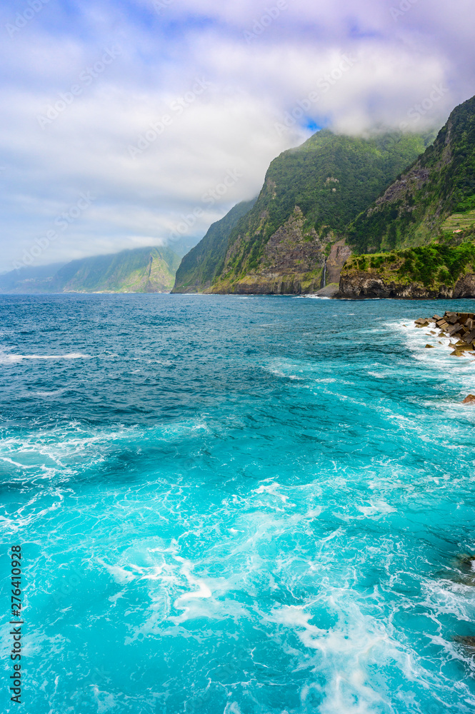 Fototapeta premium Beautiful wild coast scenery view with Bridal Veil Falls (Veu da noiva) at Ponta do Poiso in Madeira Island. Near Porto Moniz, View from Seixal, Portugal.