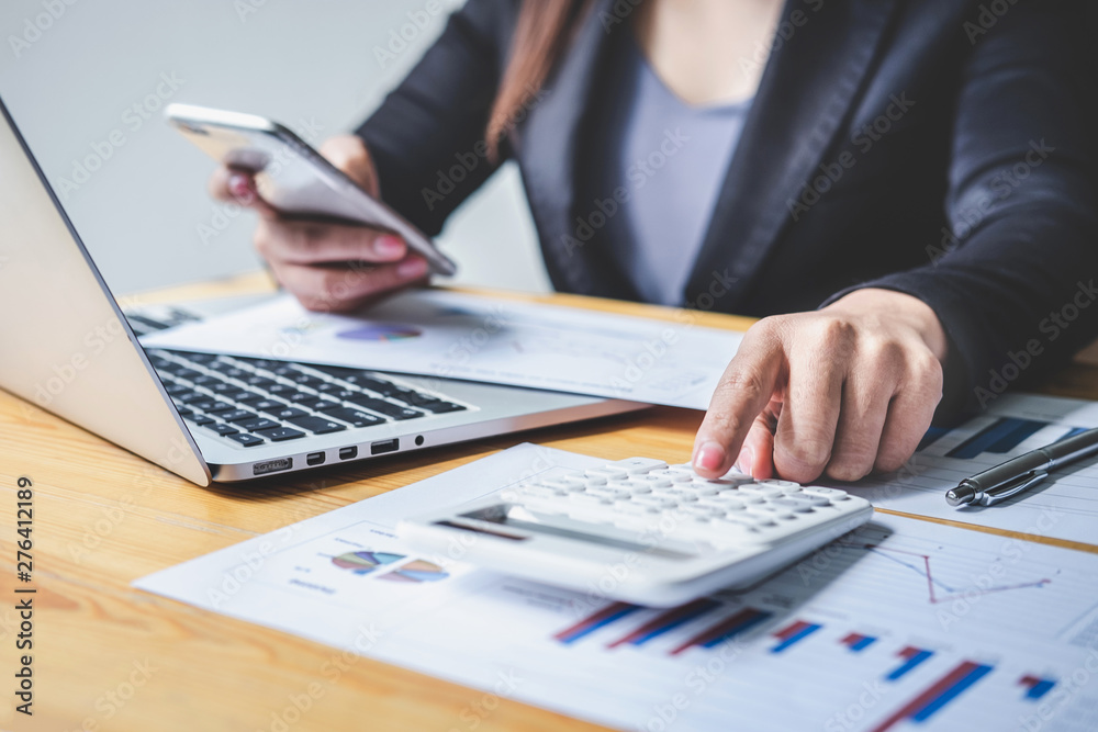 Businesswoman accountant working analyzing and calculating expense financial annual, financial balance sheet statement and analyze document graph and diagram, doing finance making notes on report Businesswoman accountant working analyzing and calculating expense financial annual, financial balance sheet statement and analyze document graph and diagram, doing finance making notes on report