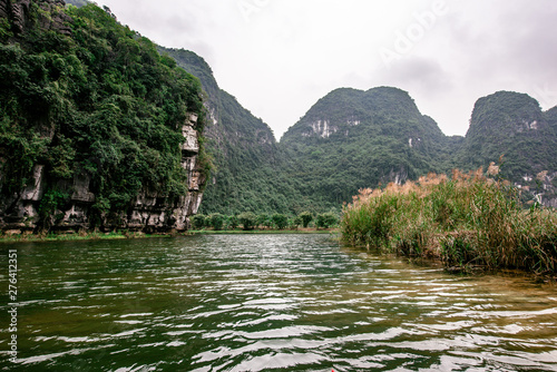 Boat cave tour in Trang An Scenic Landscape formed by karst towers and plants along the river (UNESCO World Heritage Site). It's Halong Bay on land of Vietnam. Ninh Binh province, Vietnam.