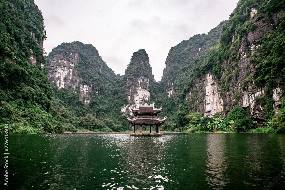 Fototapeta premium Boat cave tour in Trang An Scenic Landscape formed by karst towers and plants along the river (UNESCO World Heritage Site). It's Halong Bay on land of Vietnam. Ninh Binh province, Vietnam.