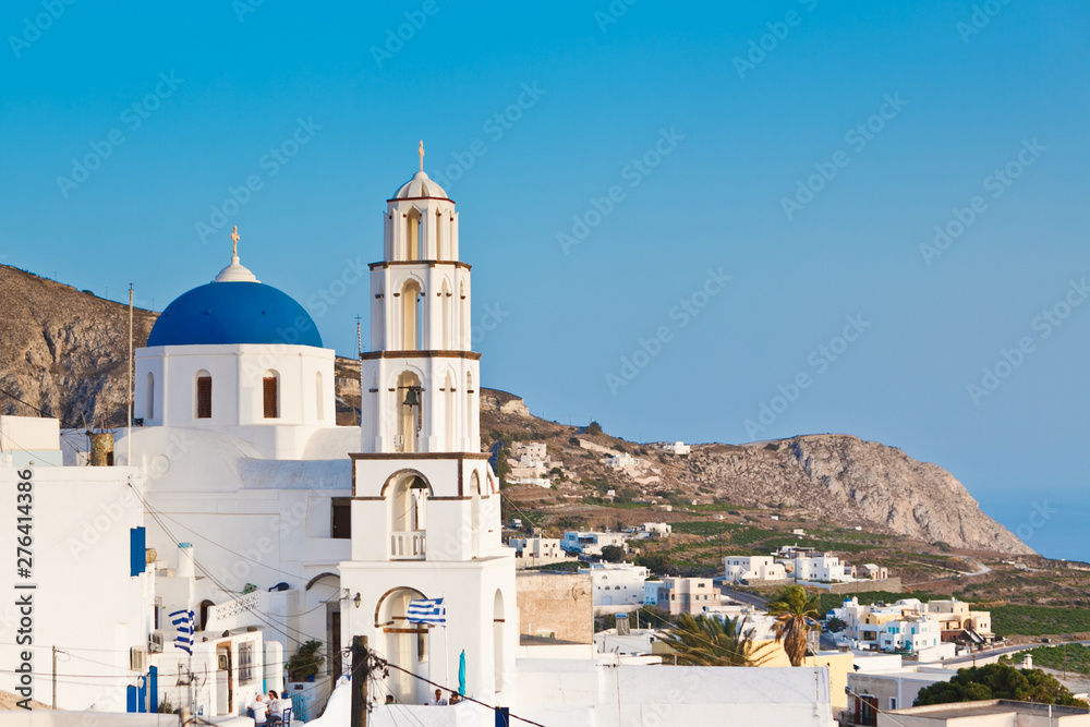 Fototapeta premium View of traditional white houses and churches with blue domes over the Caldera in Oia town on Santorini island