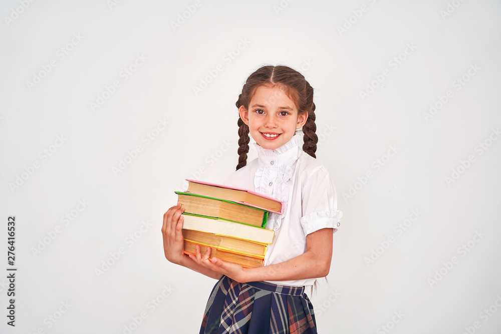 portrait of a beautiful little girl student with a backpack and a stack of books in his hands smiling on a white background. portrait of a beautiful little girl student with a backpack and a stack of books in his hands smiling on a white background.