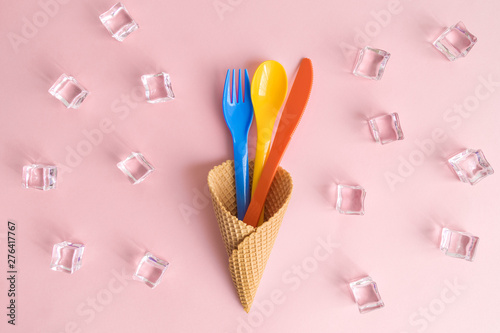 High angle view of fork, spoon and knife in ice cream cone with ice cubes isolated on rose.