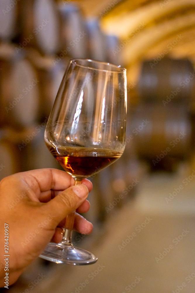Obraz premium Tasting of fortified dry or sweet marsala wine in vintage wine cellar with old oak barrels in Marsala, Sicily, Italy