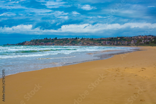 Scenic gray-blue clouds during sunrise over coastline with sandy beach and clear sea water in Agrigento, Sicily, Italy, summer vacation destination