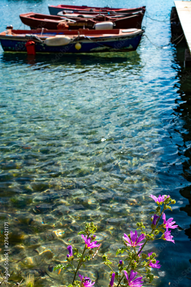 Obraz premium Seascape with pier, quiet sea harbor with clear transparent water and traditional greek fisher boats