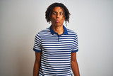 Afro man with dreadlocks wearing striped blue polo standing over isolated white background making fish face with lips, crazy and comical gesture. Funny expression.
