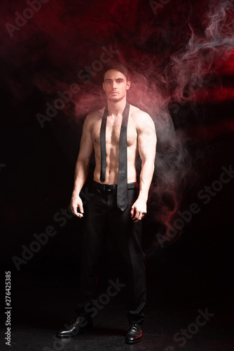 full length view of sexy shirtless man standing in smoke on black