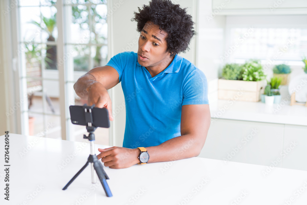 Fototapeta premium African American man doing online call with webcam using smartphone pointing with finger to the camera and to you, hand sign, positive and confident gesture from the front