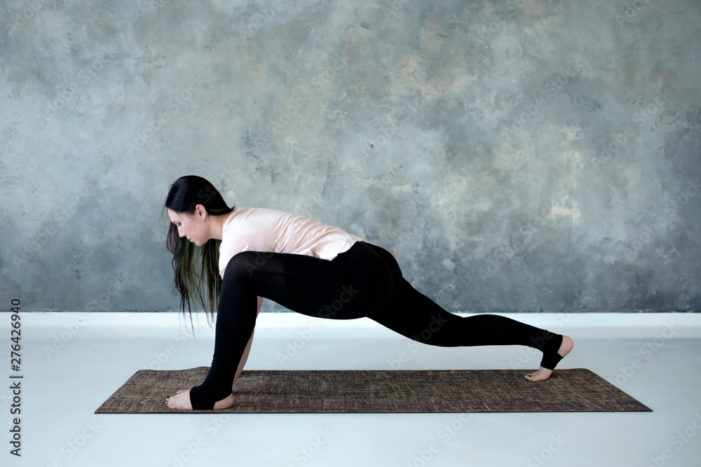 Full length profile view of woman stretching in leg lunge position. Studio shot