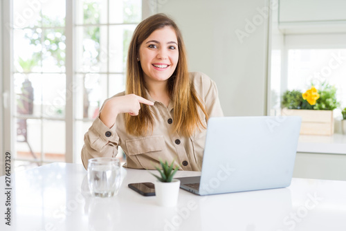 Beautiful young woman using computer laptop with surprise face pointing finger to himself