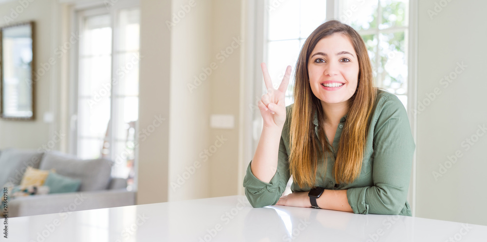 Beautiful young woman at home showing and pointing up with fingers number two while smiling confident and happy. Beautiful young woman at home showing and pointing up with fingers number two while smiling confident and happy.