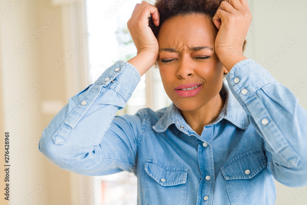Young beautiful african american woman suffering from headache desperate and stressed because pain and migraine. Hands on head. Young beautiful african american woman suffering from headache desperate and stressed because pain and migraine. Hands on head.