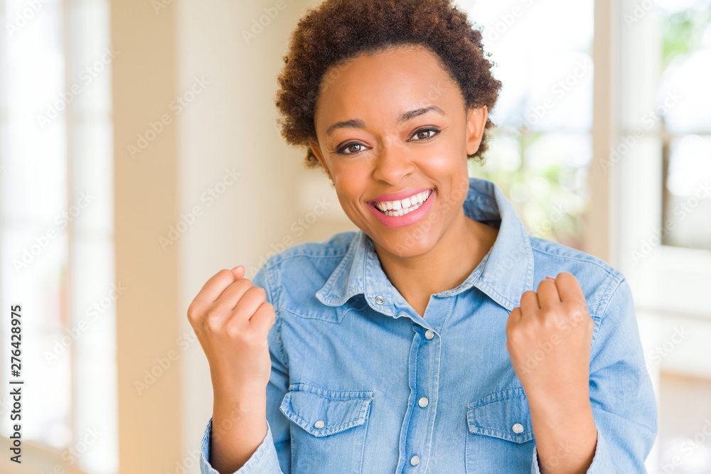 Young beautiful african american woman celebrating surprised and amazed for success with arms raised and open eyes. Winner concept. Young beautiful african american woman celebrating surprised and amazed for success with arms raised and open eyes. Winner concept.