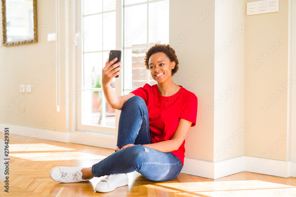 Beautiful young african american woman sitting on the floor taking a selfie smiling Beautiful young african american woman sitting on the floor taking a selfie smiling