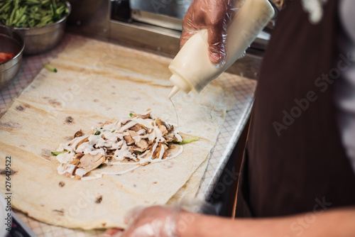 Cooking fajitos in the cafe. Cooking shawarma in pita in the kitchen. Wrap chicken, carrots, tomato in pita bread. photo