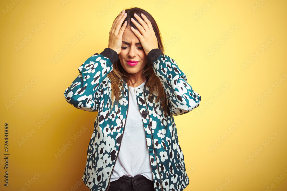 Young beautiful woman wearing casual jacket over yellow isolated background suffering from headache desperate and stressed because pain and migraine. Hands on head. Young beautiful woman wearing casual jacket over yellow isolated background suffering from headache desperate and stressed because pain and migraine. Hands on head.