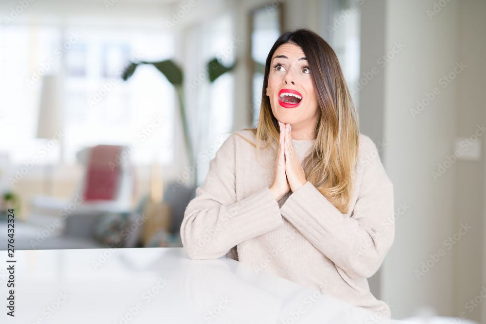 Young beautiful woman wearing winter sweater at home begging and praying with hands together with hope expression on face very emotional and worried. Asking for forgiveness. Religion concept. Young beautiful woman wearing winter sweater at home begging and praying with hands together with hope expression on face very emotional and worried. Asking for forgiveness. Religion concept.