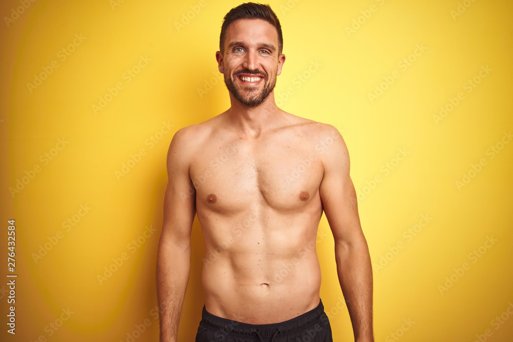 Young handsome shirtless man over isolated yellow background with a happy and cool smile on face. Lucky person.