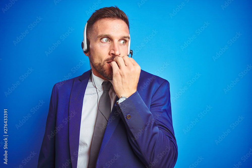 Young handsome operator man wearing call center headset over blue isolated  background looking stressed and nervous with hands on mouth biting nails.  Anxiety problem. Photos | Adobe Stock