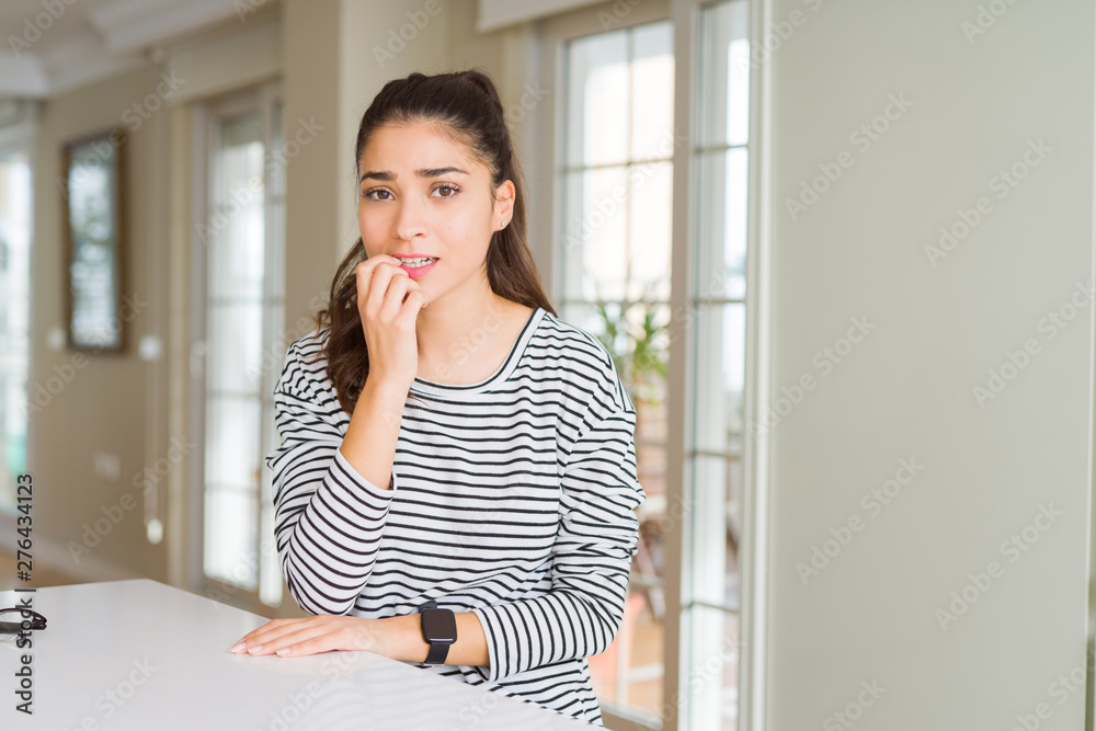Young beautiful woman at home looking stressed and nervous with hands on mouth biting nails. Anxiety problem. Young beautiful woman at home looking stressed and nervous with hands on mouth biting nails. Anxiety problem.