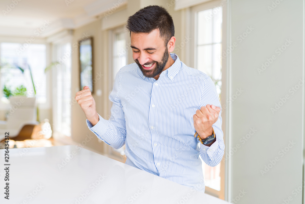 Handsome hispanic business man very happy and excited doing winner gesture with arms raised, smiling and screaming for success. Celebration concept.