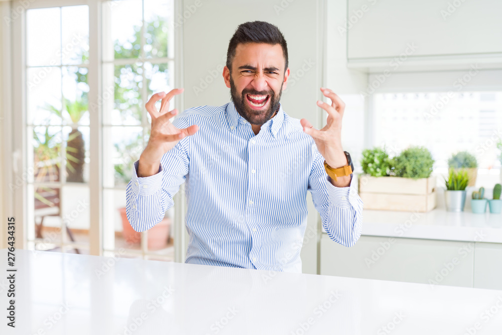 Handsome hispanic business man Shouting frustrated with rage, hands trying to strangle, yelling mad