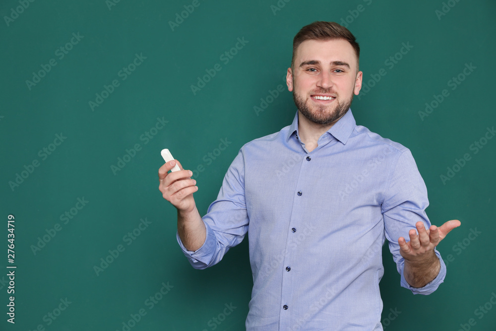 Portrait of young teacher with chalk on green background. Space for text