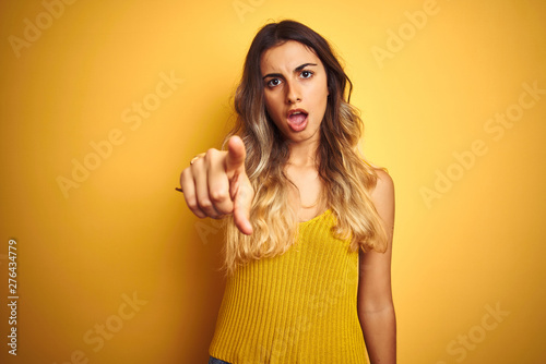 Young beautiful woman wearing t-shirt over yellow isolated background pointing displeased and frustrated to the camera, angry and furious with you
