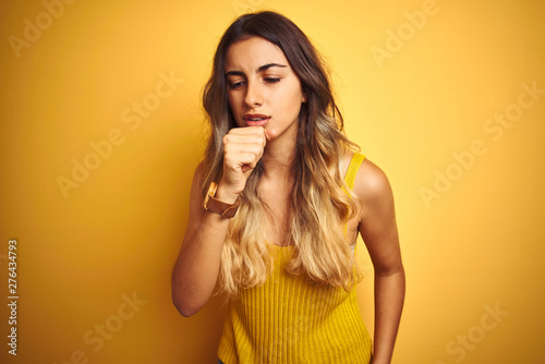 Young beautiful woman wearing t-shirt over yellow isolated background feeling unwell and coughing as symptom for cold or bronchitis. Healthcare concept.