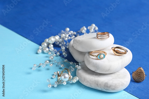 White marble stones with elegant jewelry on color background. Space for text photo