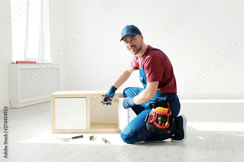 Obraz na płótnie Handyman in uniform assembling furniture indoors