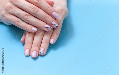 Fashionable feminine art, beautiful unique nail manicure on a blue background