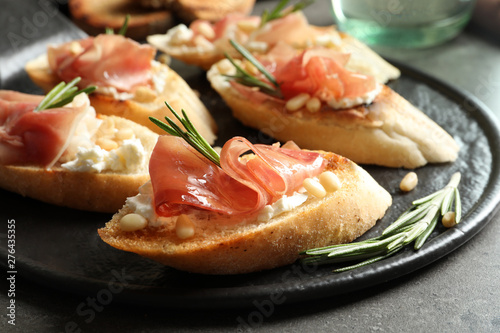 Tasty bruschettas with prosciutto and cream cheese served on table, closeup