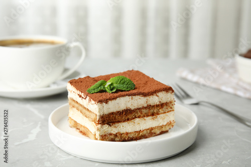 Delicious tiramisu cake with cup on table