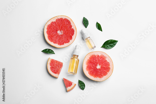 Composition with grapefruit slices and bottles of essential oil on white background, top view photo