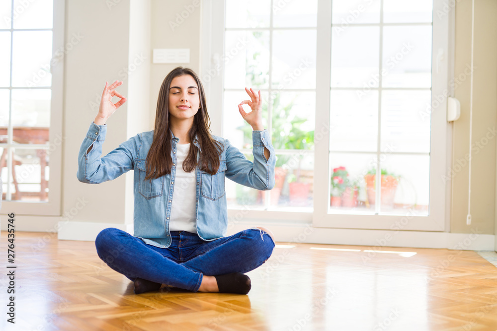 Beautiful young woman sitting on the floor at home relax and smiling with eyes closed doing meditation gesture with fingers. Yoga concept. Beautiful young woman sitting on the floor at home relax and smiling with eyes closed doing meditation gesture with fingers. Yoga concept.