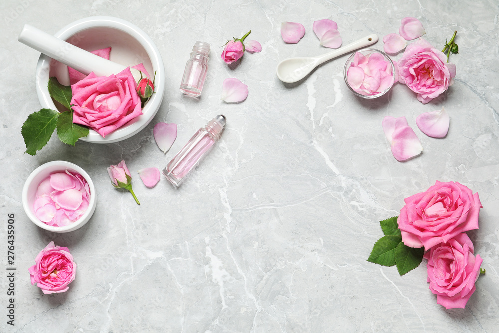 Flat lay composition with rose essential oil and fresh flowers on grey table, space for text Flat lay composition with rose essential oil and fresh flowers on grey table, space for text