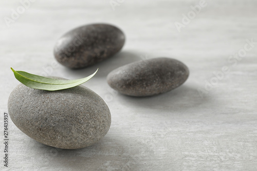 Spa stones with green leaf on grey background. Space for text
