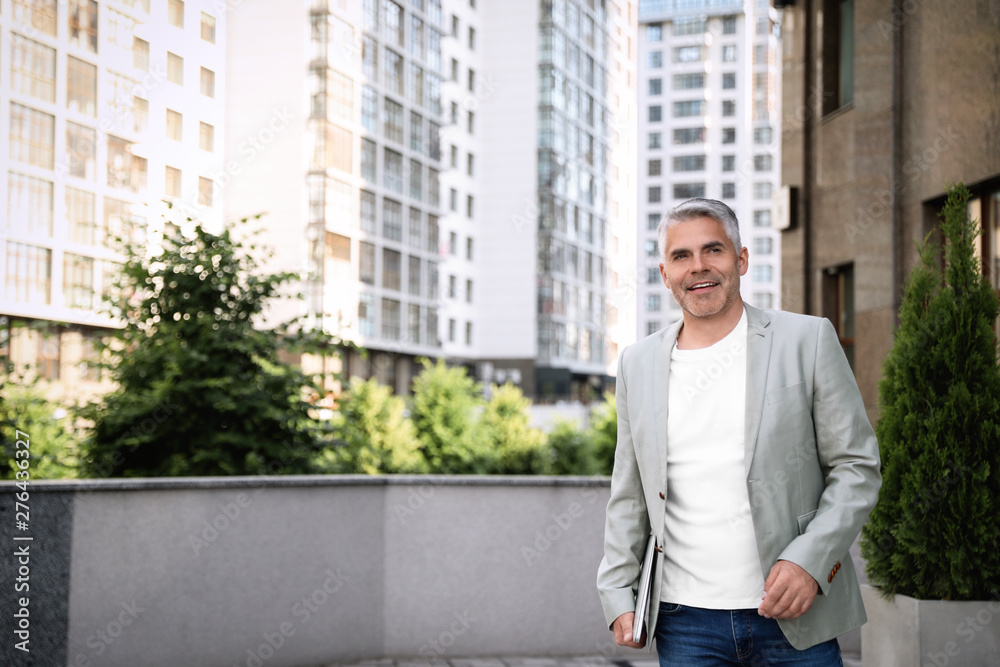 Portrait of handsome mature man with laptop in city center. Space for text Portrait of handsome mature man with laptop in city center. Space for text
