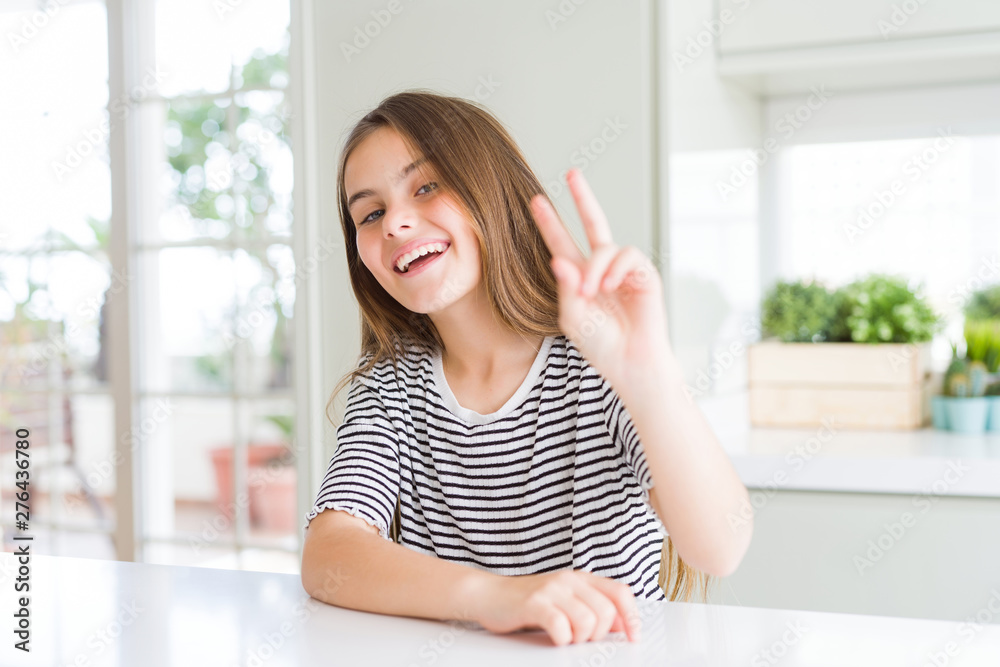 Beautiful young girl kid wearing stripes t-shirt smiling looking to the camera showing fingers doing victory sign. Number two.
