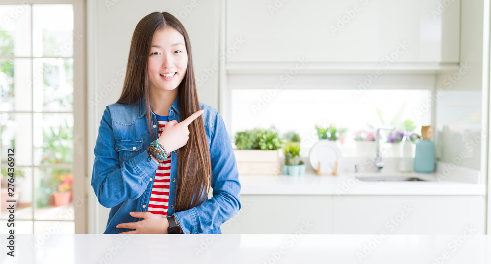 Beautiful Asian woman wearing denim jacket on white table cheerful with a smile of face pointing with hand and finger up to the side with happy and natural expression on face Beautiful Asian woman wearing denim jacket on white table cheerful with a smile of face pointing with hand and finger up to the side with happy and natural expression on face