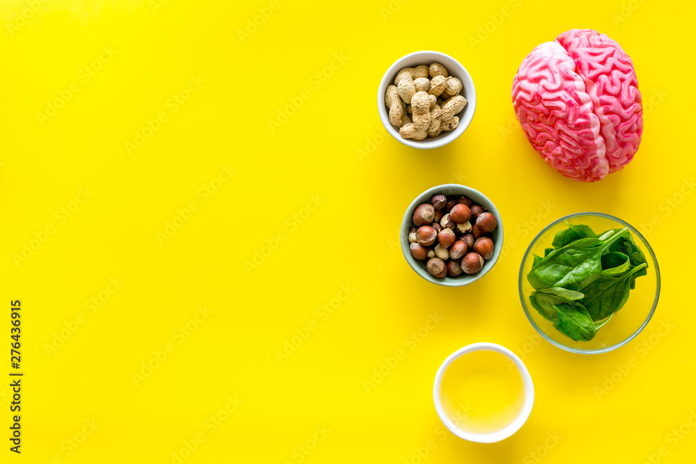 Brain food concept with peanut, hazelnut, seed-oil, spinage on yellow background top view copyspace