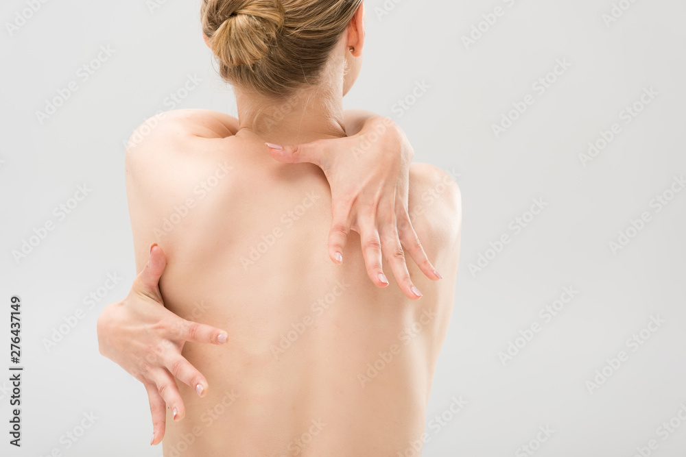 back view of naked woman embracing herself isolated on grey back view of naked woman embracing herself isolated on grey