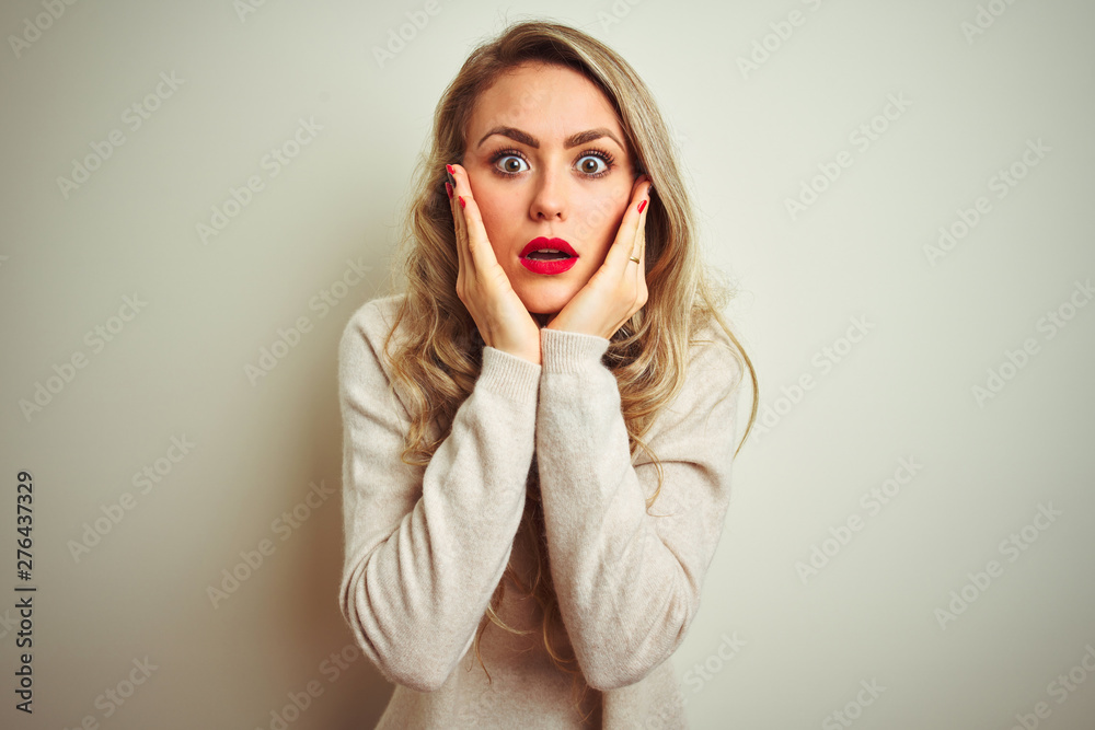 Beautiful woman wearing winter turtleneck sweater over isolated white background afraid and shocked, surprise and amazed expression with hands on face Beautiful woman wearing winter turtleneck sweater over isolated white background afraid and shocked, surprise and amazed expression with hands on face