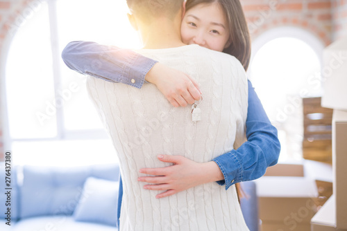 Young asian couple holding keys of new house, smiling happy and excited moving to a new apartment