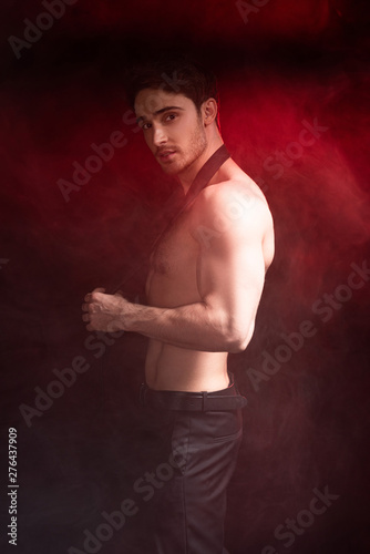 shirtless sexy muscular man looking at camera in red smoke